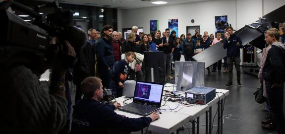 Viele Besucher und Besucherinnen bei Jena-Optronik. Das Bild zeigt die Echtzeit-Simulation eines Sensors an einen Satelliten.